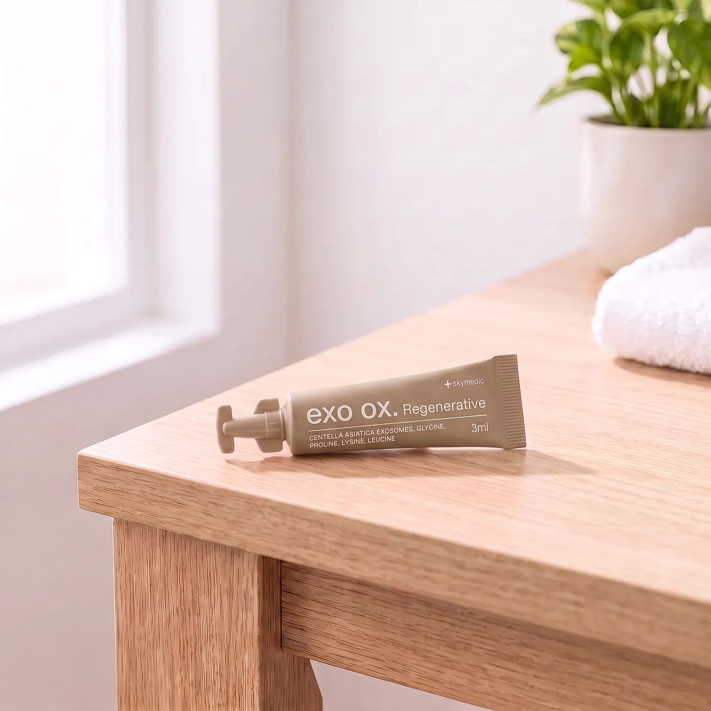 A taupe 3 ml tube of exo ox. Regenerative by Skymedic, made with Centella asiatica exosomes, on a light oak desk
